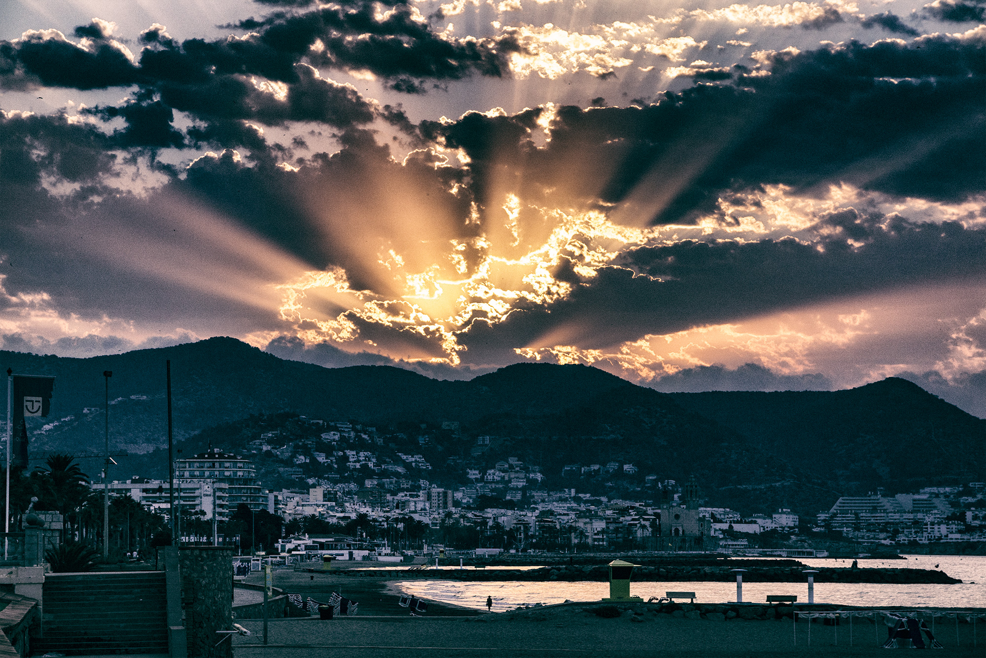 Sonnenaufgang in Sitges, Spanien. Die Sonne glüht über Bergen.