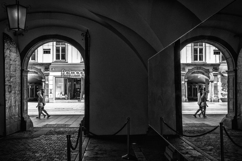 Blick vom Landhaushof in die Herrengasse in Graz. Personen in der Herrengasse spiegeln sich in einem Kustwerk aus einem Spiegel.