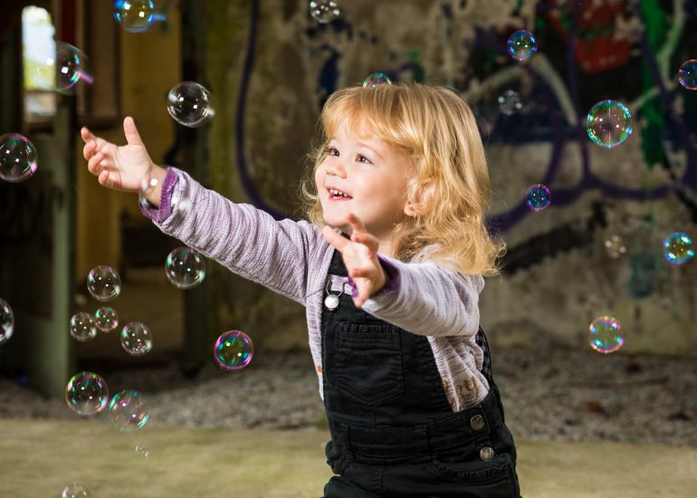 Ein Kleinkind jagd Seifenblasen hinterher