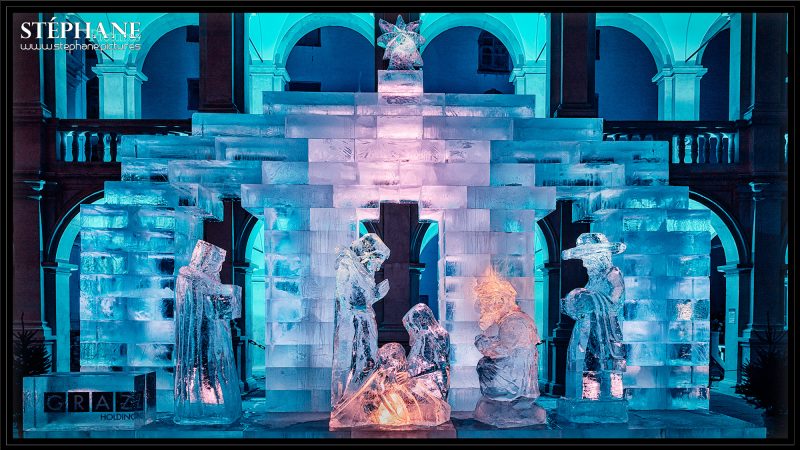 Blick auf die Grazer Eiskrippe. Im Hintergrund erkennt man die Arkaden des großen Landhaushofes. Das Bild erstrahlt in Blau-, Orange- und Rosatönen.