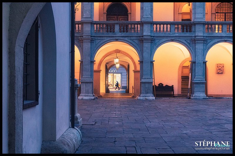 Blick vom kleinen Landhaushof über den großen Landhaushof in Richtung Herrengasse. Eine Person geht gerade in der Herrengasse entlang.
