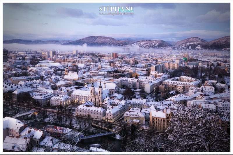 Blick vom Schloßberg über die mit Schnee bedeckten Dächer der Stadt
