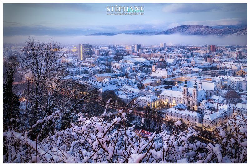 Blick vom Schloßberg über die mit Schnee bedeckten Dächer der Stadt